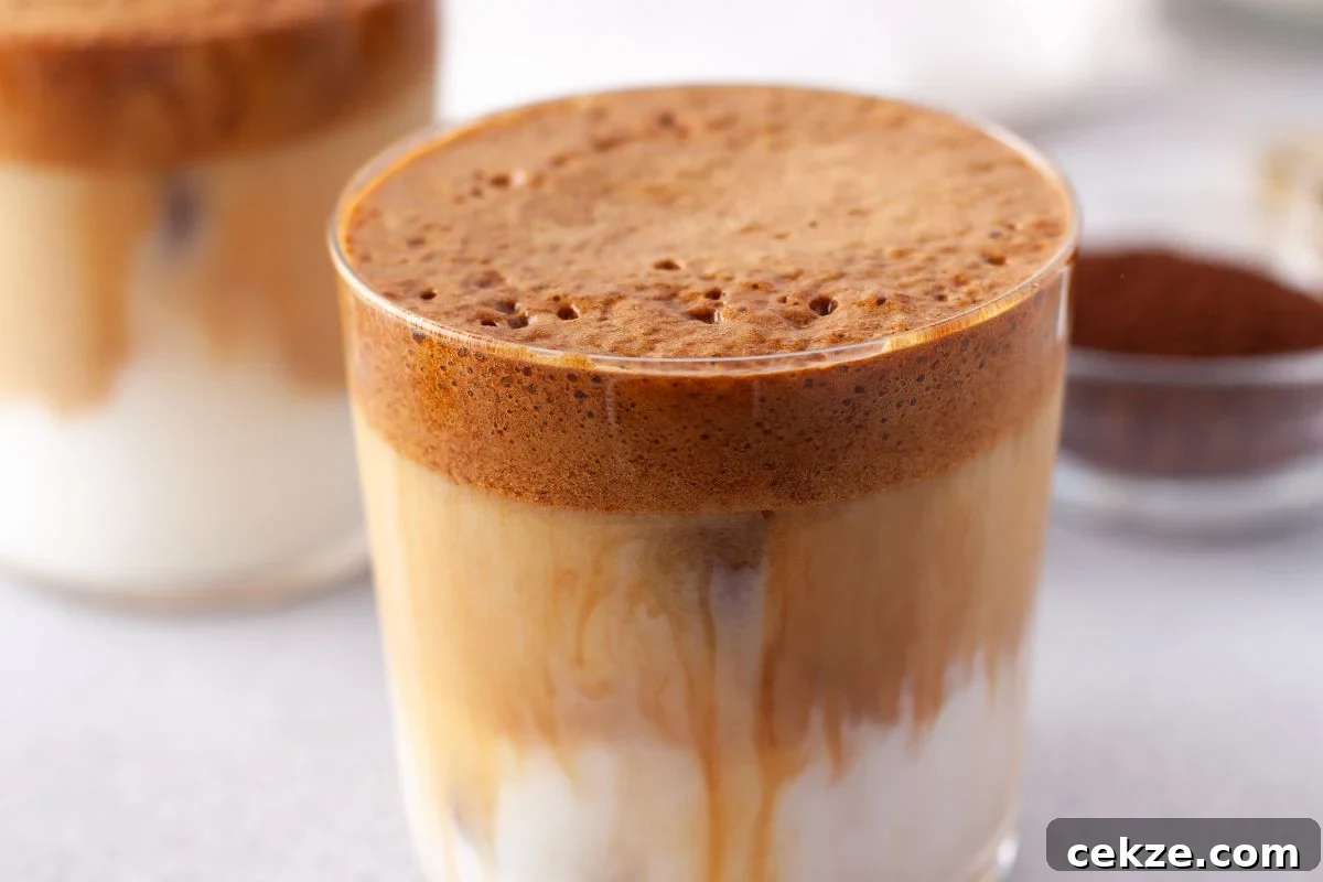 49 TikTok Recipes That Truly Live Up to the Hype 37 A glass of Pumpkin Spice Whipped Dalgona Coffee with creamy foam on top and milk beneath, perfect for a cozy seasonal coffee recipe, sits on a light surface.