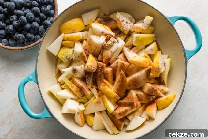 Pear and Blueberry Crisp Recipe for Warm, Fruity Dessert 5 Chopped pears simmering in a skillet with maple syrup, vanilla, and spices.