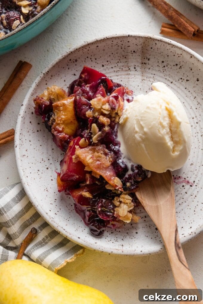 Pear and Blueberry Crisp Recipe for Warm, Fruity Dessert 9 Small dish of pear blueberry crisp topped with vanilla ice cream.