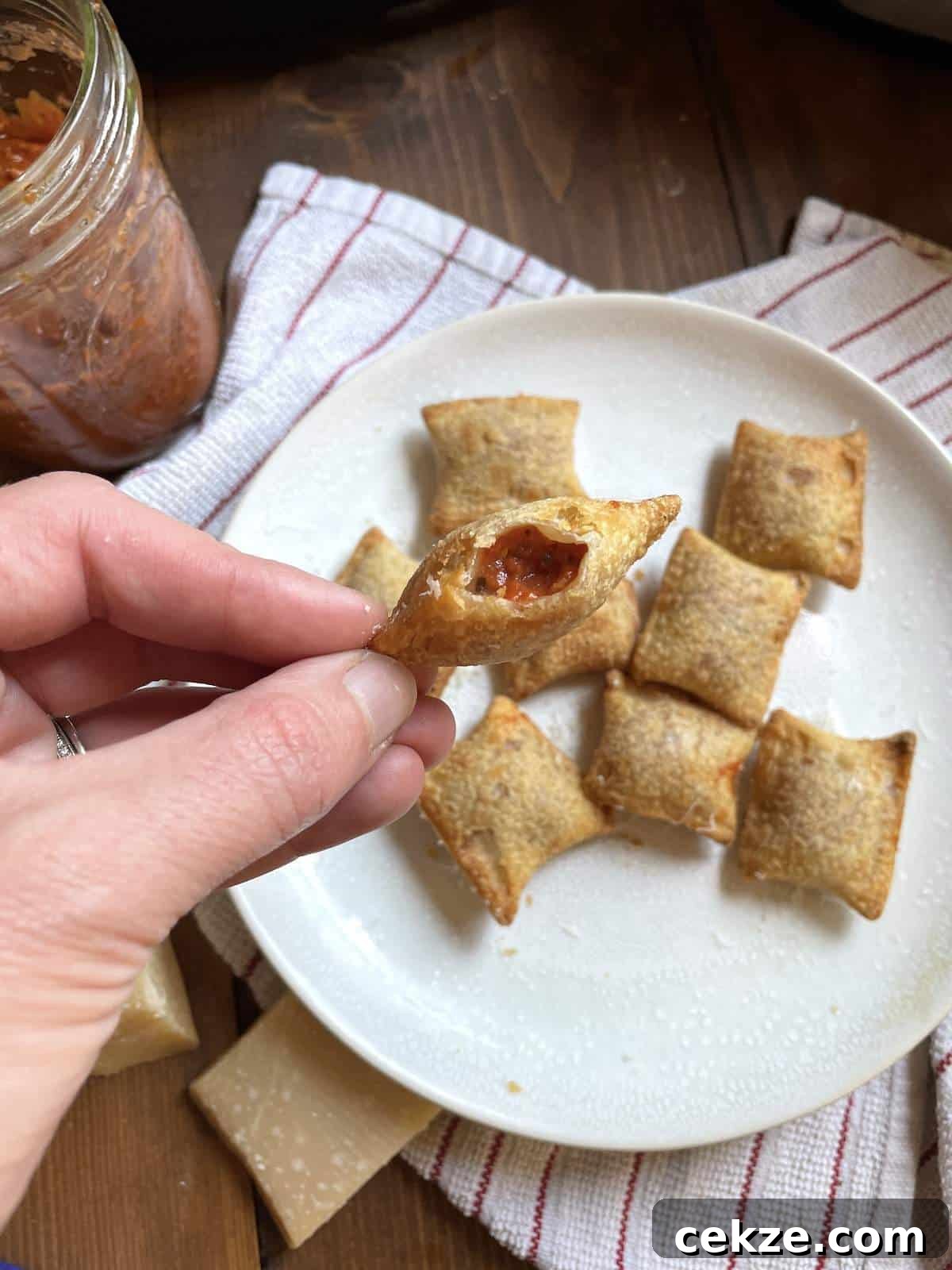 An air fried pizza roll bit open showing the inside over a plate of pizza bites.