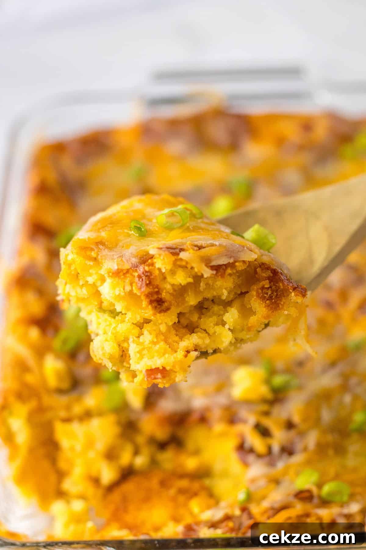 Loaded Cornbread Casserole Recipe — Cheesy Bacon & Jalapeño Bake 3 spoonful of loaded cornbread casserole held in the air.