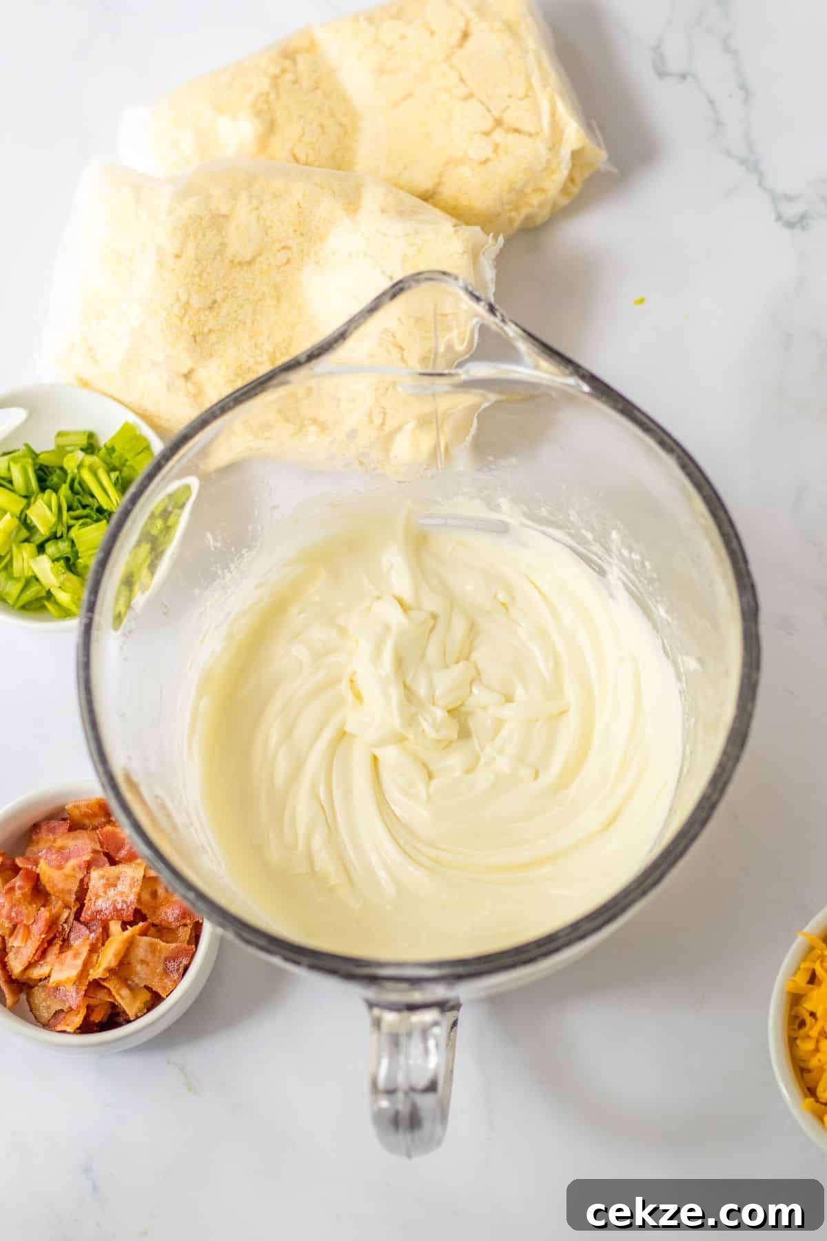 Loaded Cornbread Casserole Recipe — Cheesy Bacon & Jalapeño Bake 5 cream cheese and butter being melted in a glass mixing bowl.