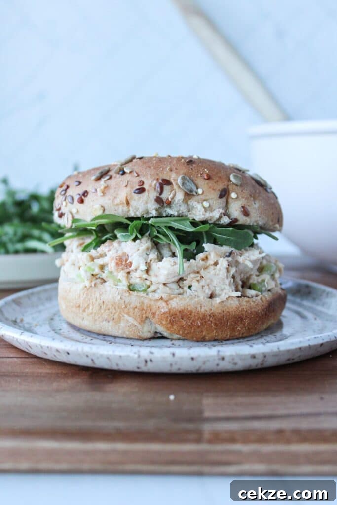 A whole grain bun with arugula and 4-ingredient chicken salad on a plate.