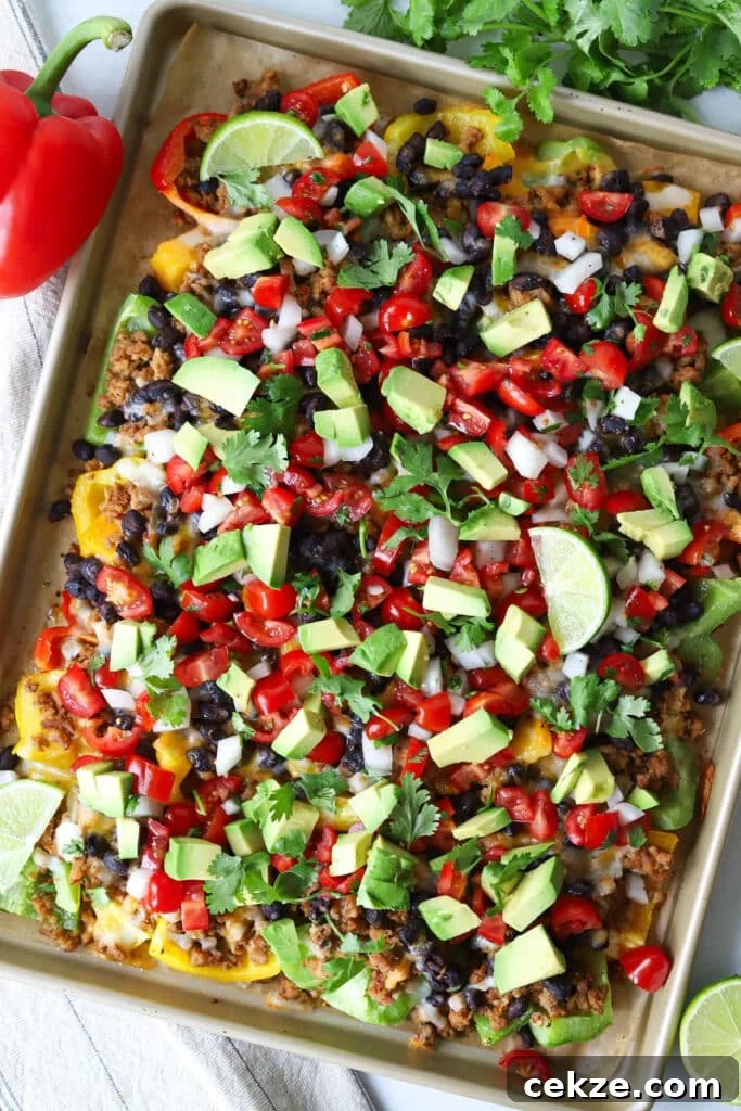 Bell pepper nachos on a sheet pan topped with pico de gallo, avocado and cilantro.