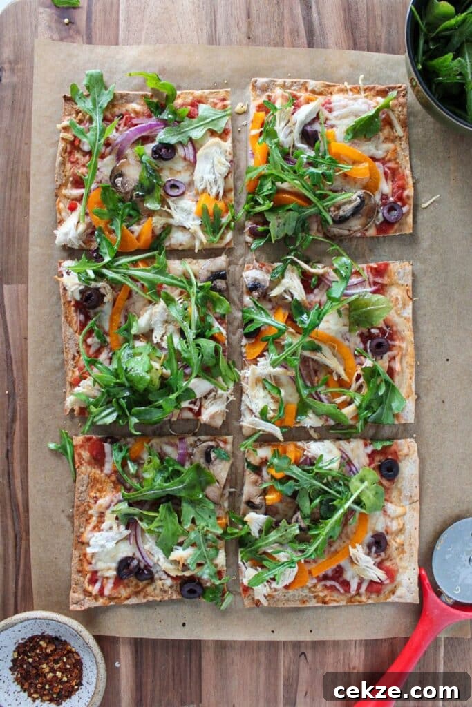 Lavash bread pizza topped with arugula and cut into slices.