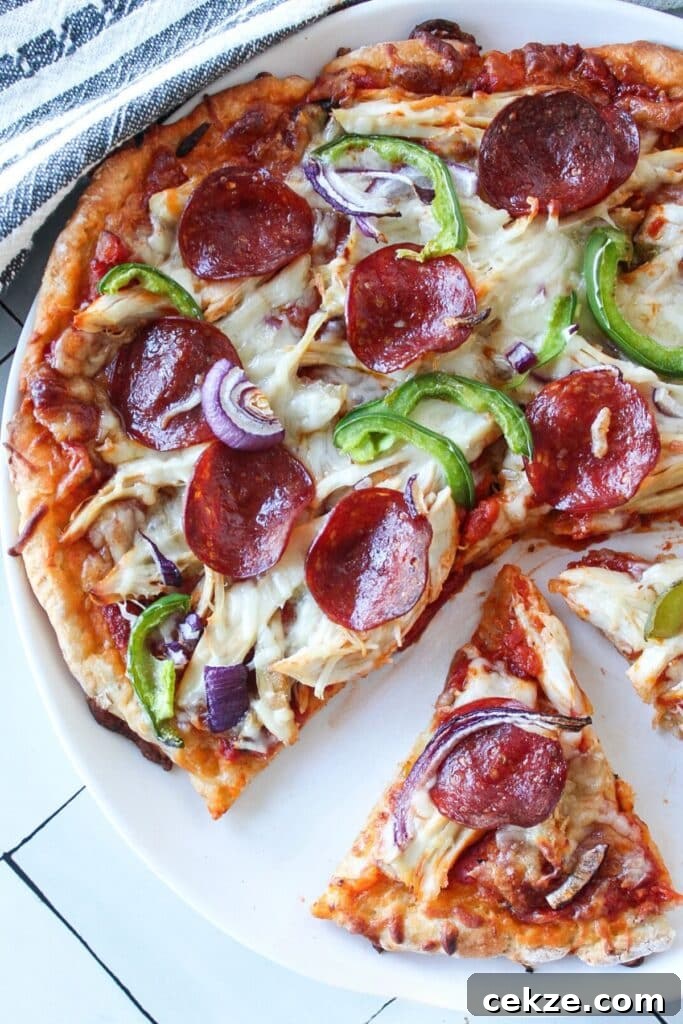 High protein pizza with two slices cut on a white plate on a countertop.