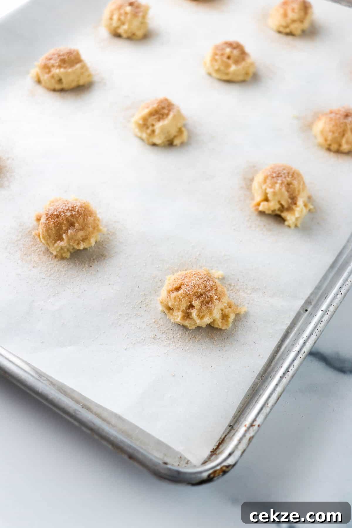 Unbaked Old-Fashioned Buttermilk Cookies on a baking sheet sprinkled with cinnamon and sugar.