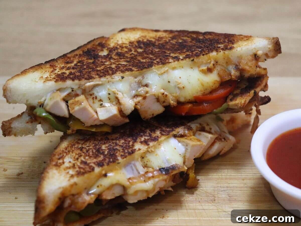 Image of chicken fajita sandwich stacked and placed on a chopping board with a a small bowl of tomato ketchup on the side.