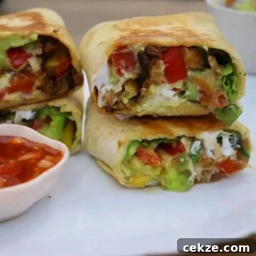 chicken fajita wrap. They are sliced and stacked on a white plate. Served with salsa dip.