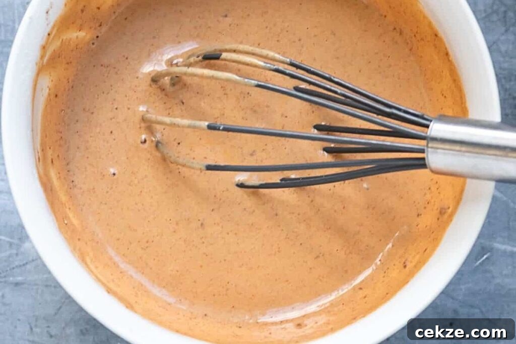 A bowl of chipotle sauce, with a whisk in it.