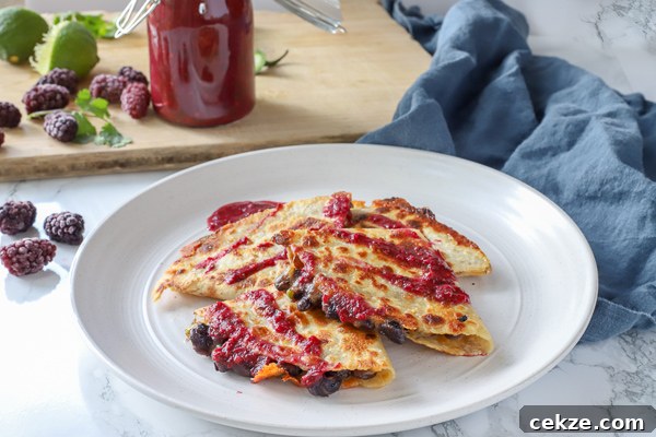 black bean quesadillas with blackberry enchilada sauce on a stone plate on a blue napkin