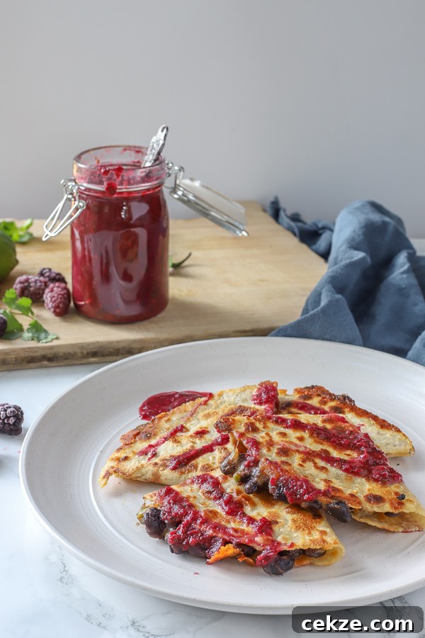 black bean quesadillas topped with blackberry enchilada sauce on a stone plate