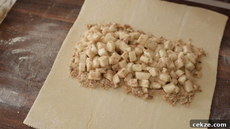 Placing apple and walnut filling on top of breadcrumb mixture on puff pastry