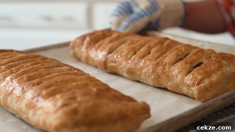 Two puff pastry apple strudels baked to golden brown on a sheet pan