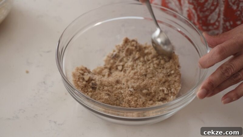 Mixing breadcrumbs and chopped walnuts in a bowl for apple strudel filling.