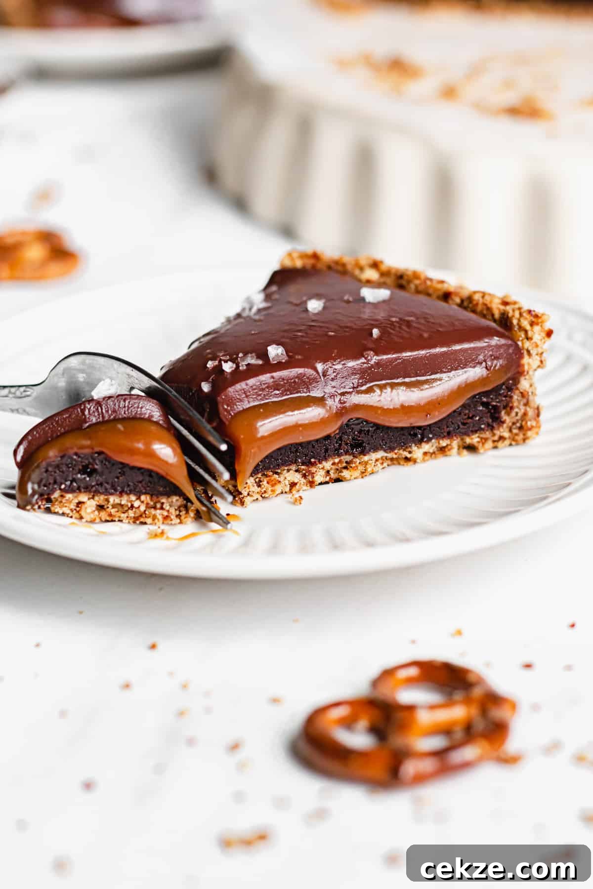 Slice of chocolate caramel tart with a fork removing the tip.