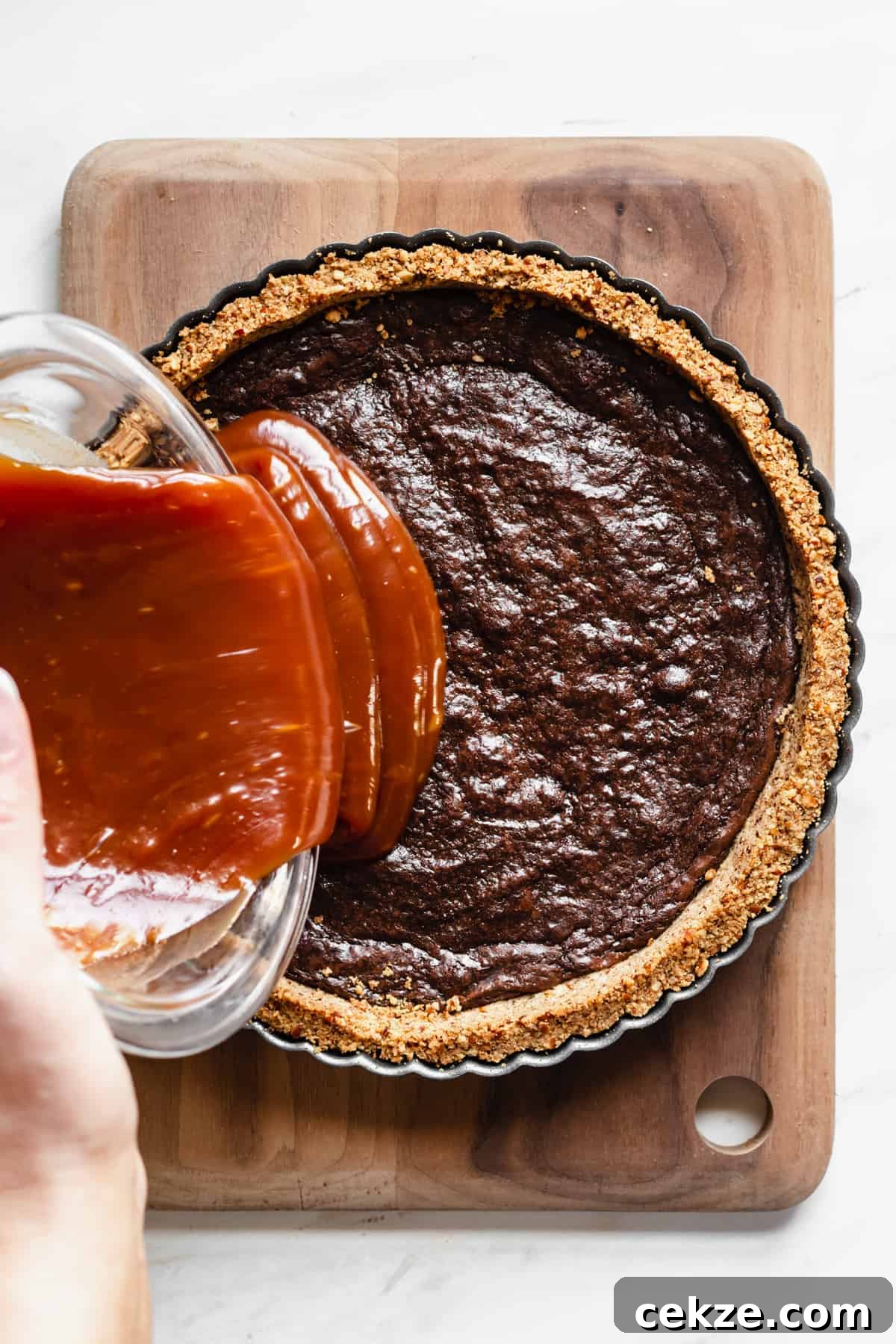 Caramel being added to the brownie layer