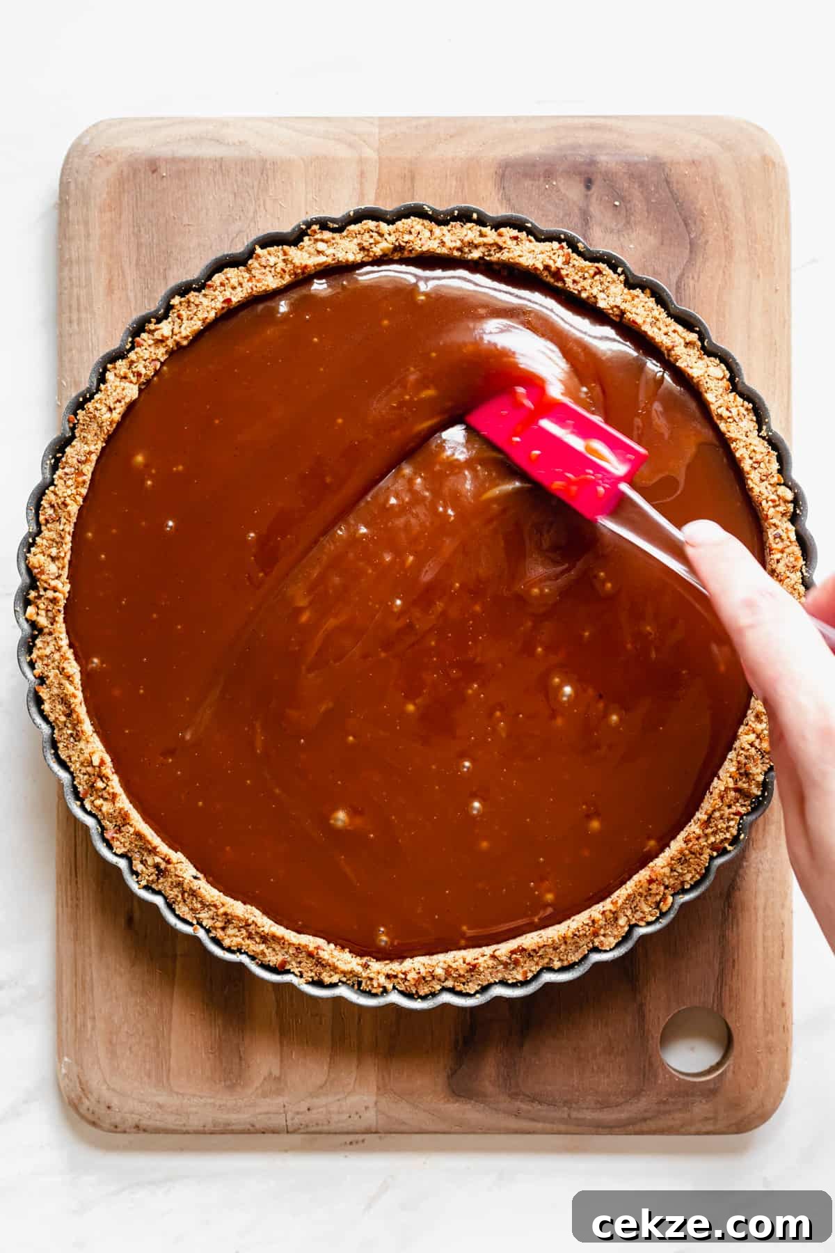 Caramel being spread to meet the edges of the pie
