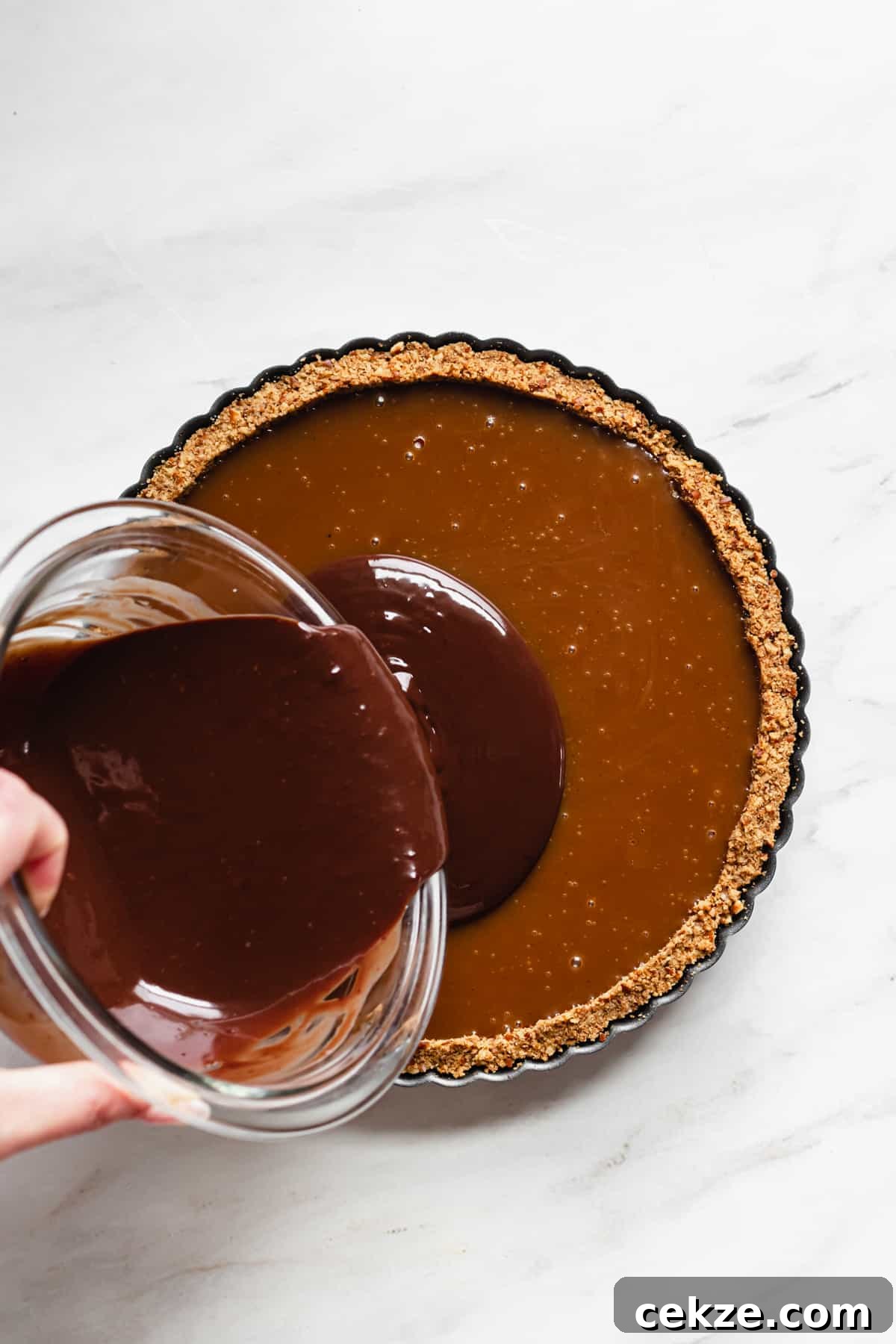 Chocolate ganache being poured onto the set caramel