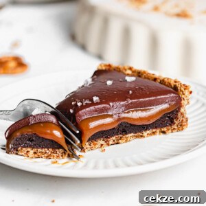 A fork cuts into a piece of caramel tart on a plate.