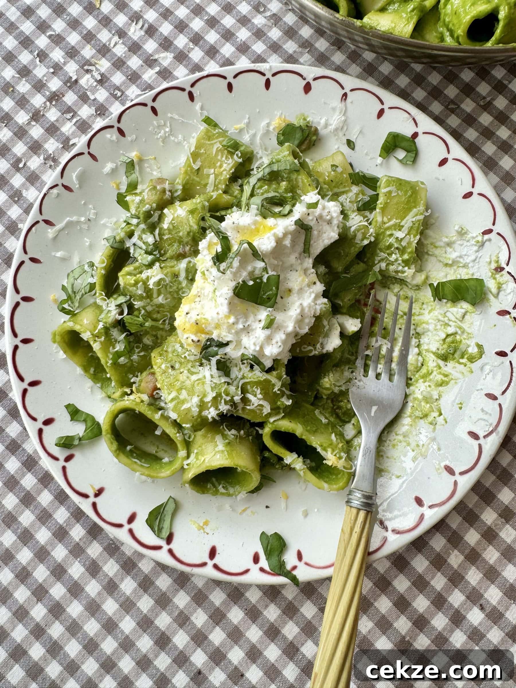 Creamy Spinach Pesto Pasta with Garlic and Lemon 2 pasta in green sauce on a plate topped with cheese