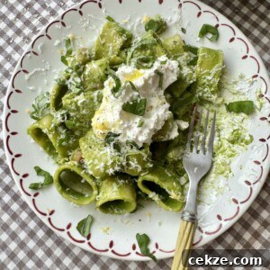 Creamy Spinach Pesto Pasta with Garlic and Lemon 12 pasta in green sauce on a plate topped with cheese