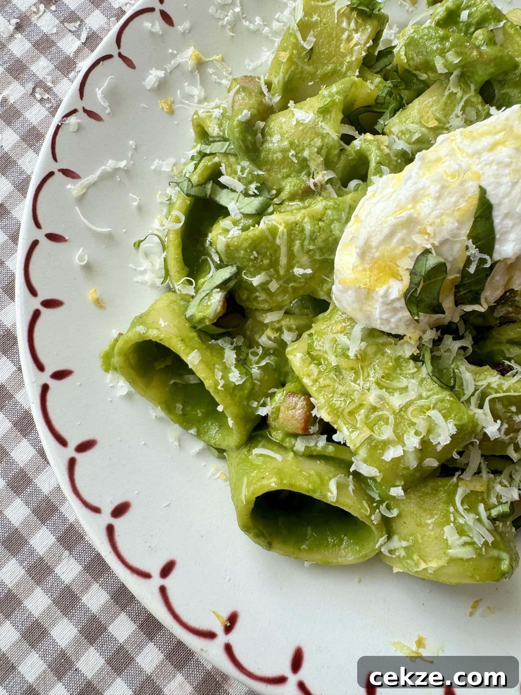 Creamy Spinach Pesto Pasta with Garlic and Lemon 10 pasta in green sauce on a plate topped with cheese