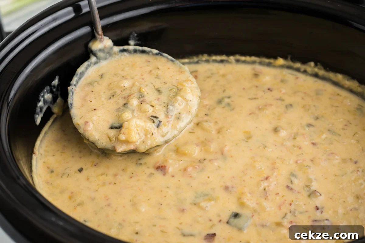 Slow cooker bacon ranch potato soup with a ladle taking a scoop.