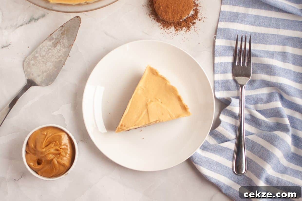 A slice of Peanut Butter & Chocolate Pie on a white plate, with a fork, a small bowl of peanut butter, a baking tool, and a striped napkin nearby.