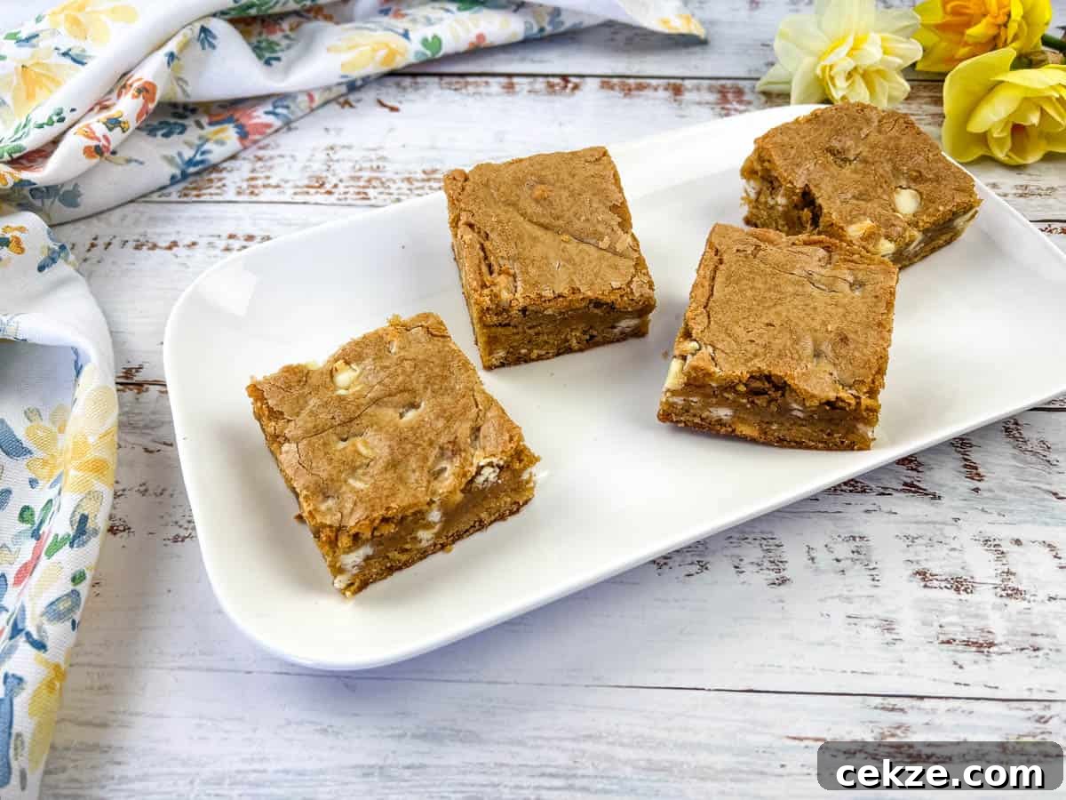 A white plate with four square pieces of Speculoos White Chocolate Blondies bars.