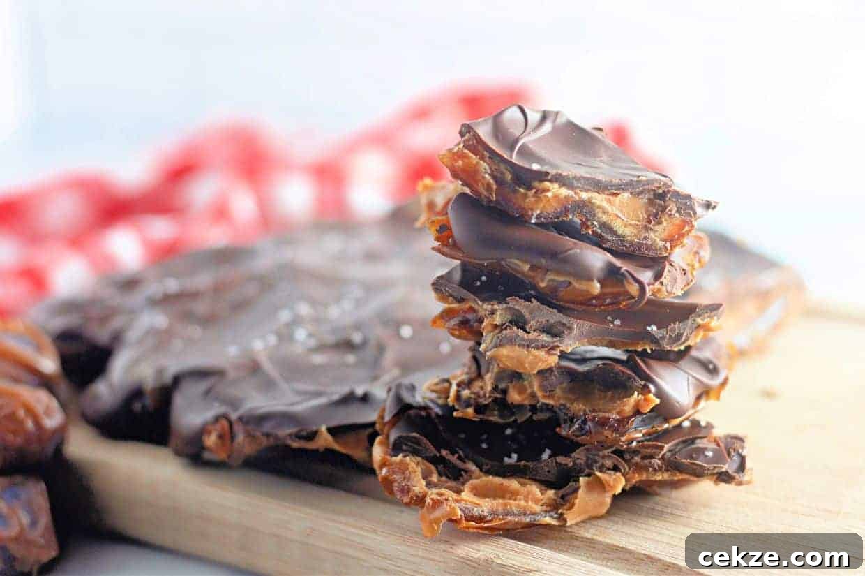 A stack of Peanut Butter and Date Chocolate Bark pieces sits on a wooden board.