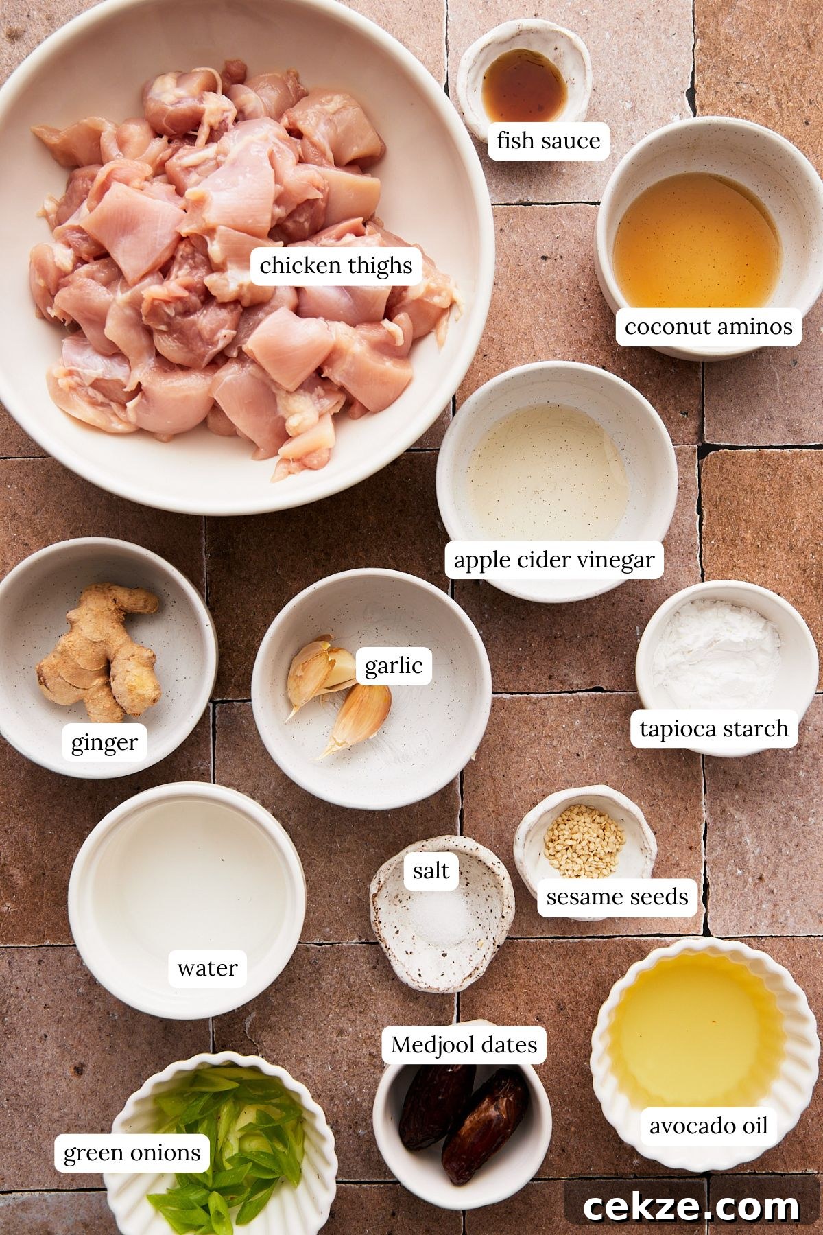 recipe ingredients for sesame chicken in small ramekins and labeled, including diced chicken, seasonings, and oil. 