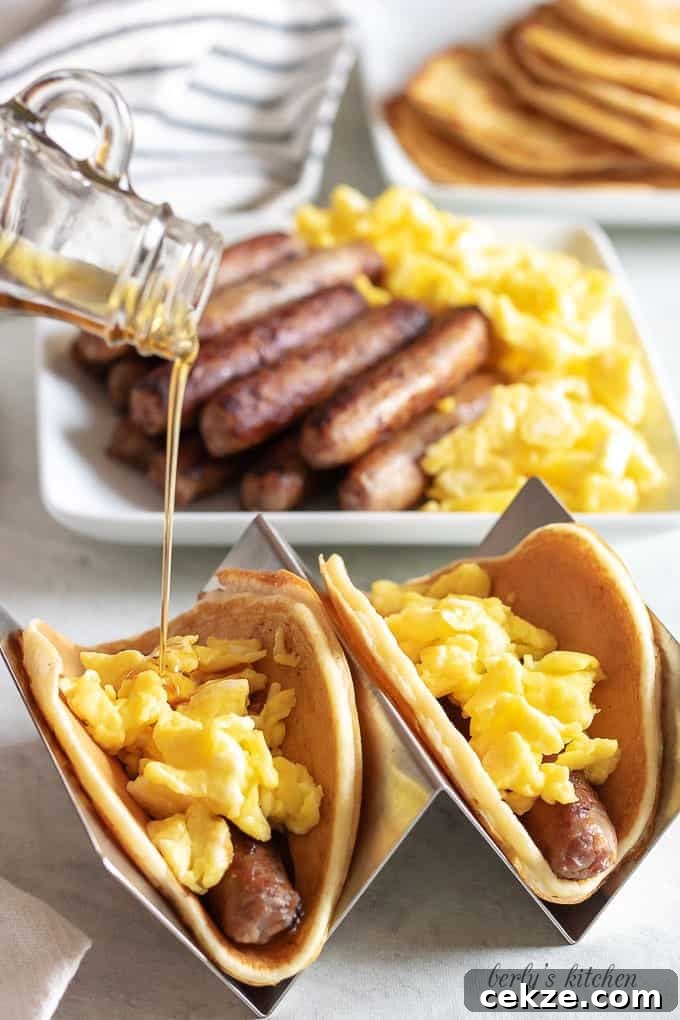 The tacos have been built with sausage and eggs, and topped with maple syrup.