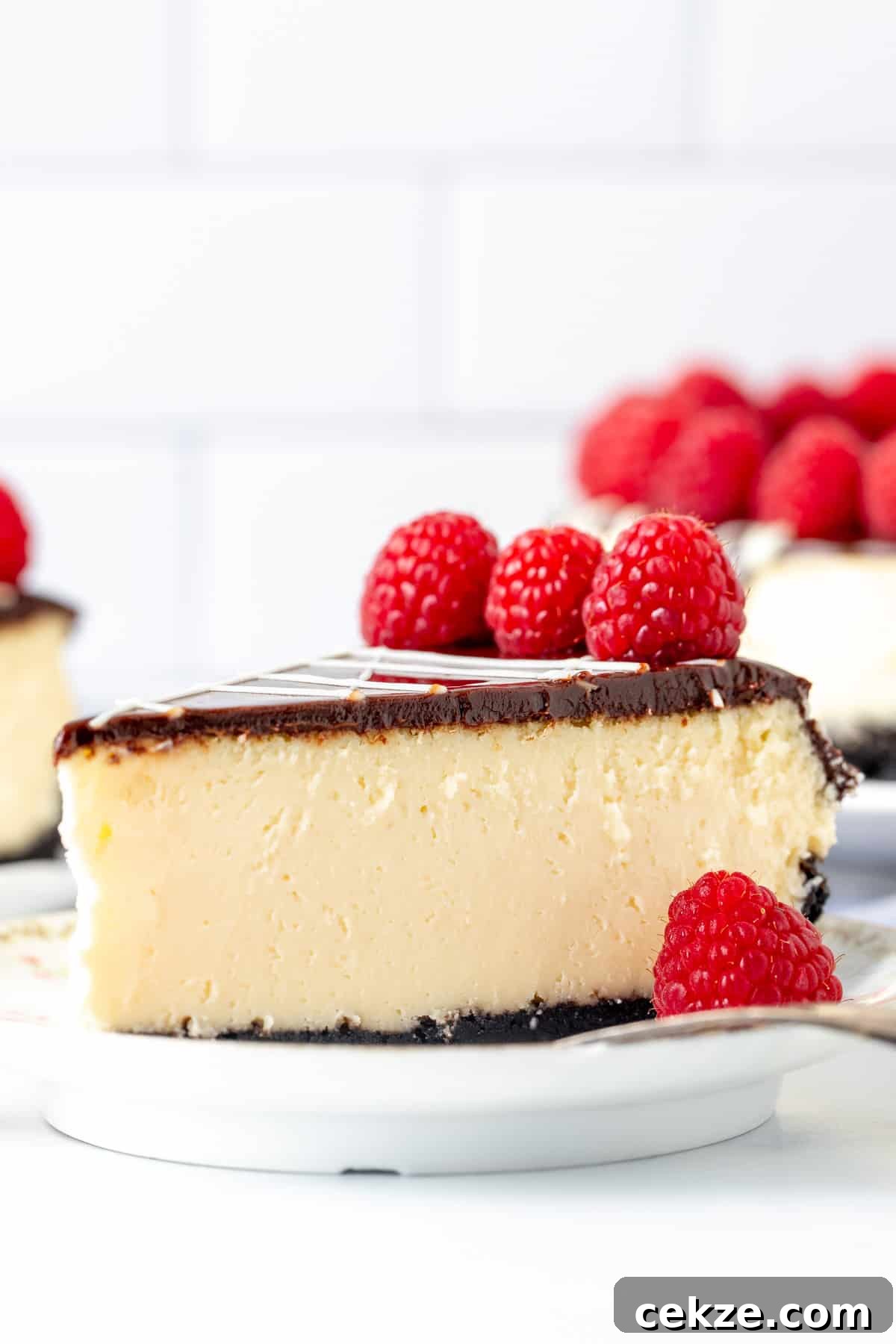 Slice of white chocolate cheesecake with Oreo crust and chocolate topping