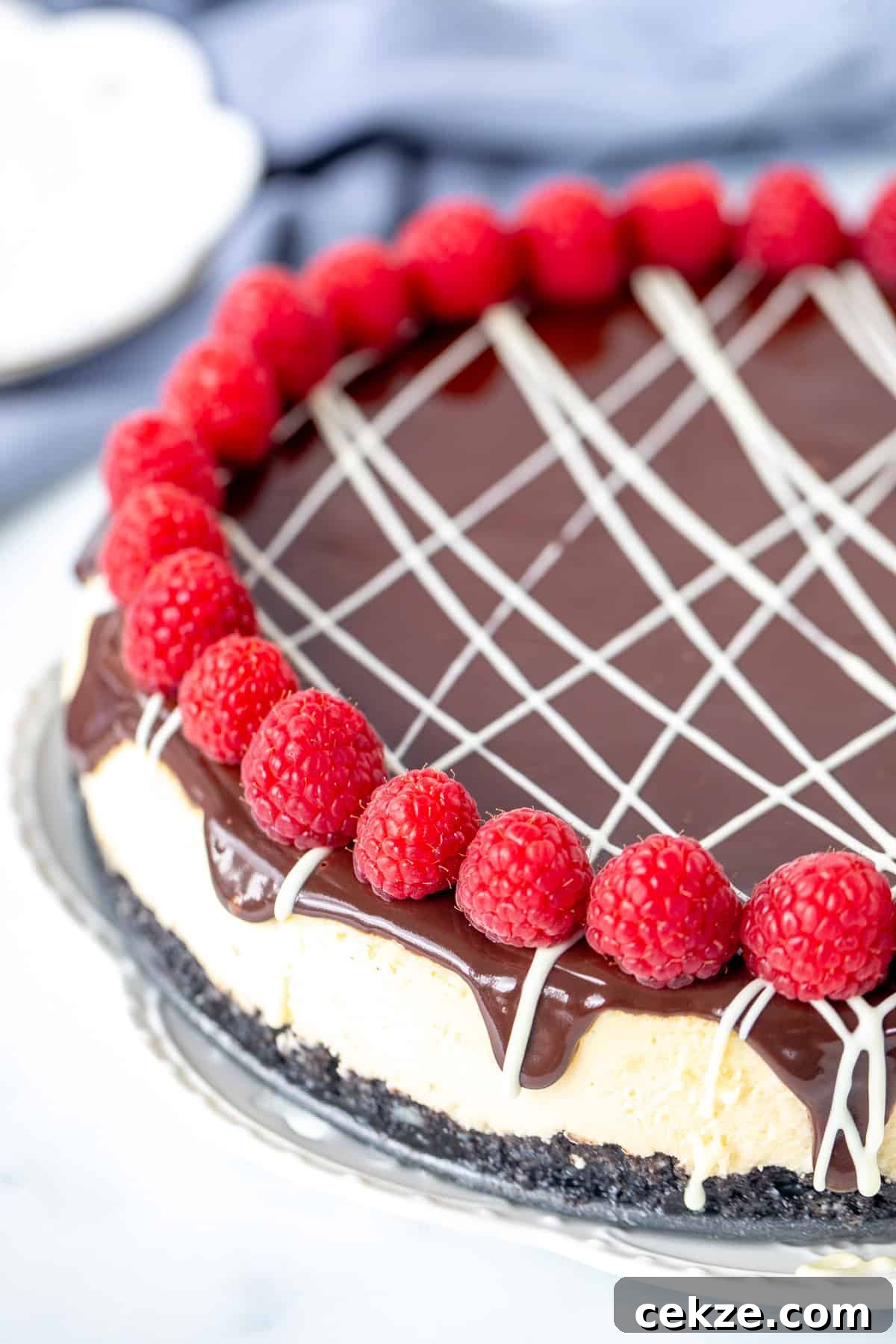 White chocolate cheesecake with chocolate topping, drizzle of white chocolate and raspberries around the edges