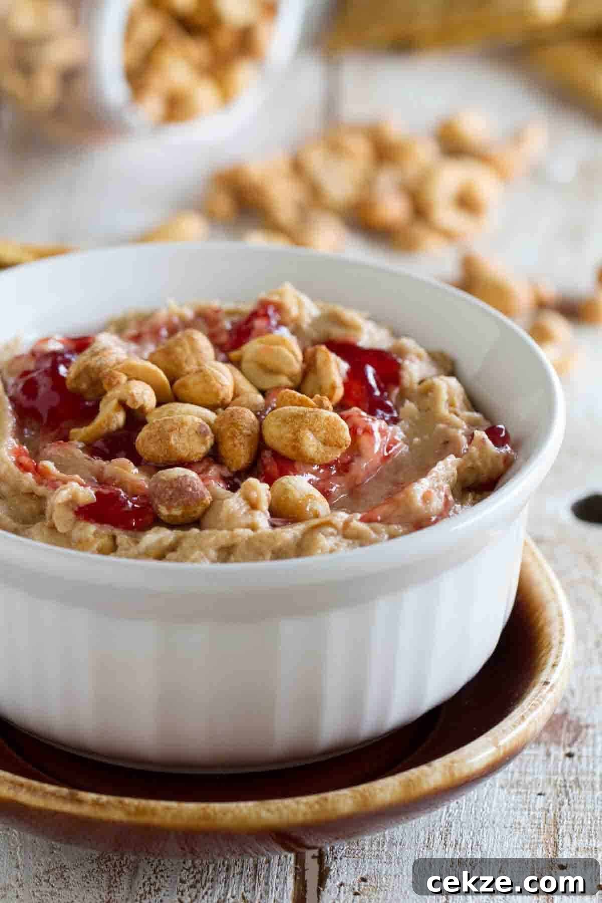 Bowl with peanut butter and jelly dip topped with peanuts and jelly.