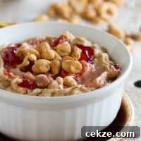 Bowl with peanut butter and jelly dip topped with peanuts and jelly.