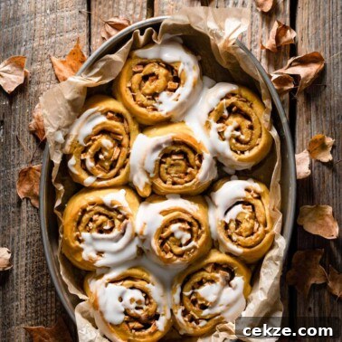 Tray filled with pumpkin sweet rolls topped with frosting.