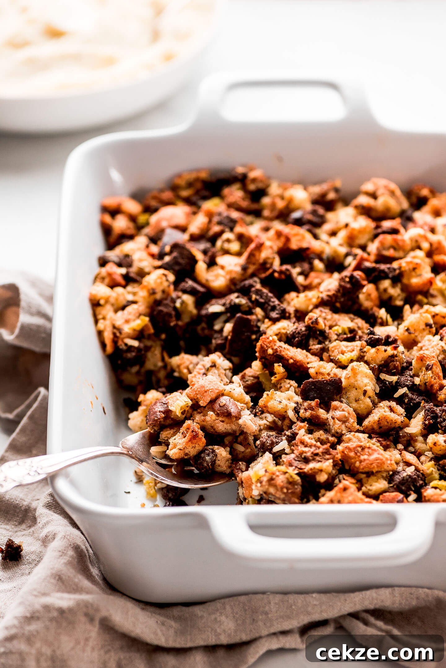 Scooping a spoonful of Turkey Stuffing out of a casserole dish.