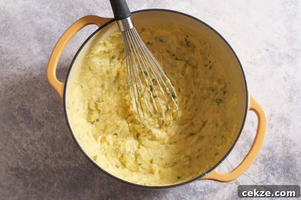 A dutch oven with a whisk and spoonbread dough.