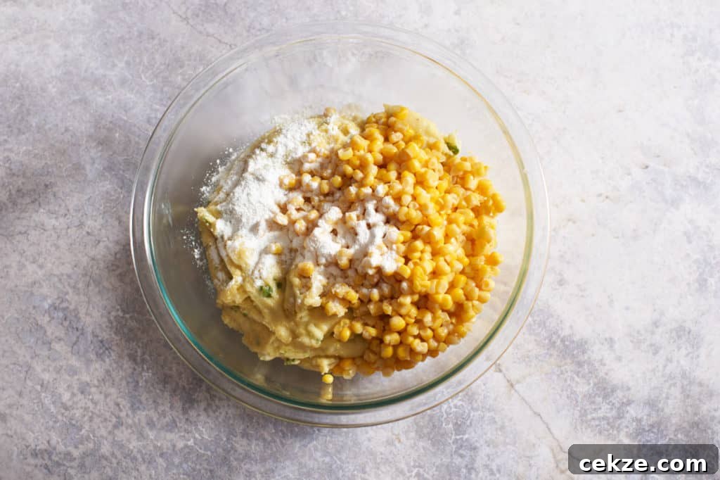 A glass bowl with spoonbread dough, corn, and baking powder.