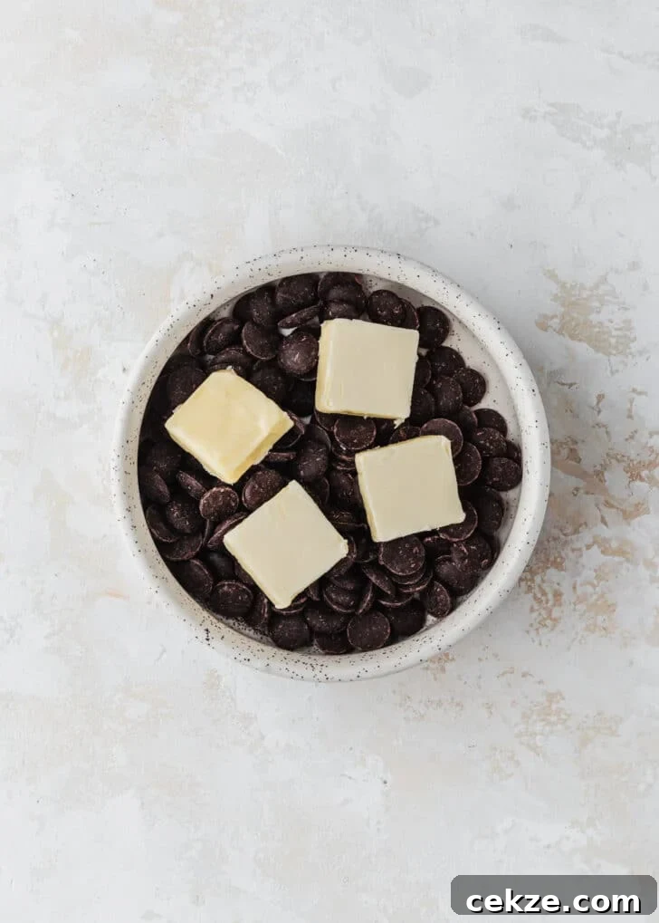 A white bowl of chocolate chips and butter on a beige table.