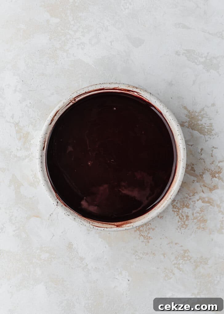 A white bowl of melted chocolate on a white counter.