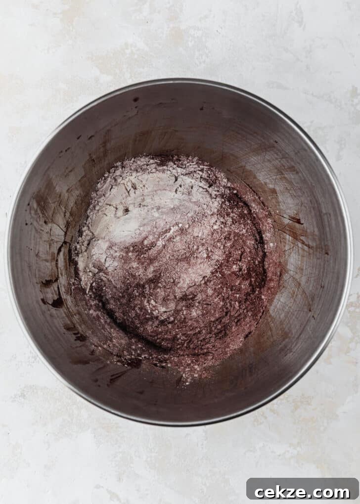 A silver bowl of flour and cocoa powder on a tan counter.