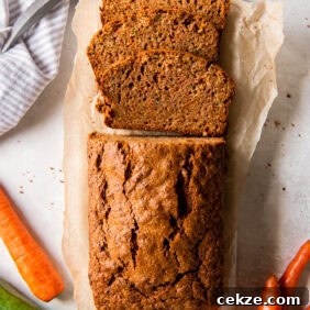 tabletop with loaf of zucchini carrot bread with three slices cut off the end.