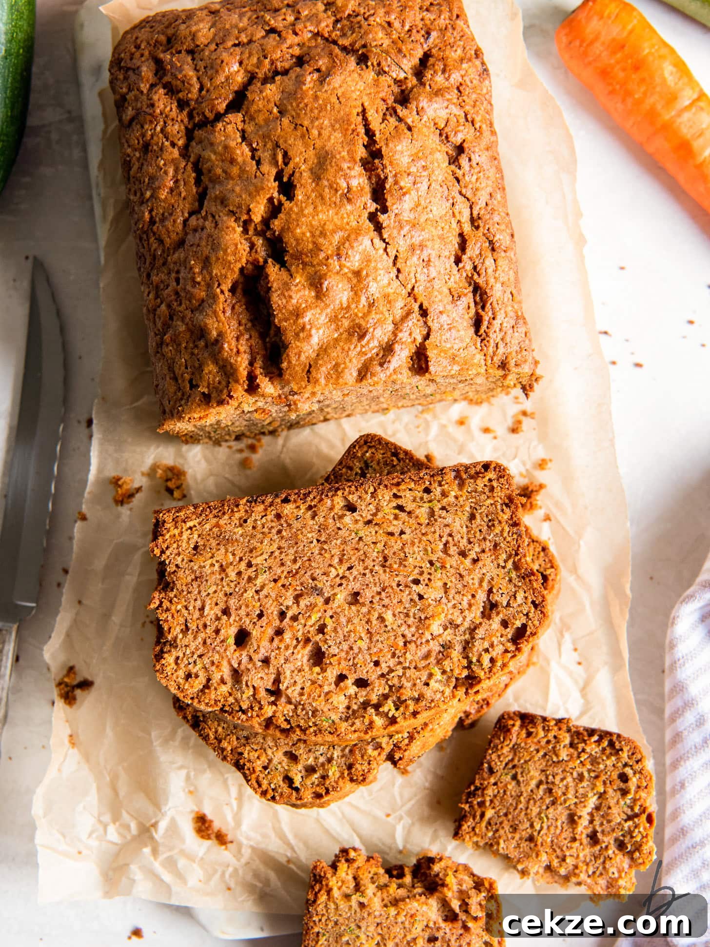 tabletop with loaf of zucchini carrot bread next to stack of a couple slices.