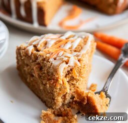 Slice of carrot cake coffee cake on a white plate with a fork.