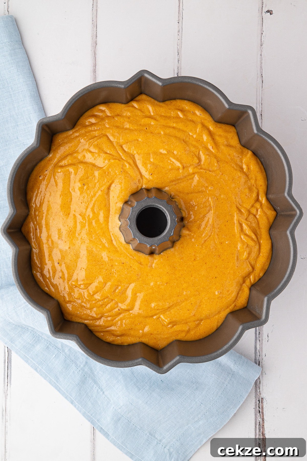 pumpkin cake batter poured into greased bundt cake pan